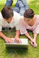 Two friends looking at something on a laptop while lying down