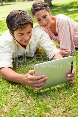 Two friends smiling as they watch something on a tablet together