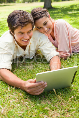 Woman leans against her friend as they use a tablet together