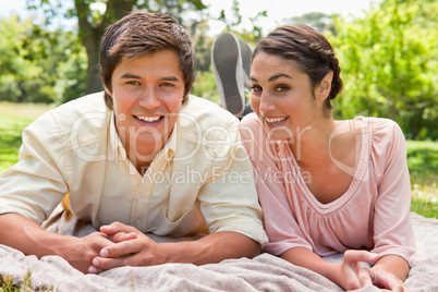 Two friends looking ahead while lying on a blanket