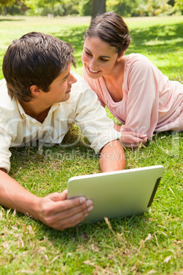 Two friends looking at each other while using a tablet together