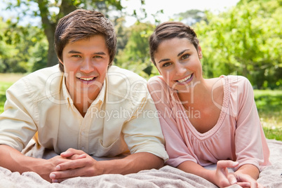 Two friends looking smiling while lying on a blanket