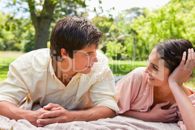 Two friends looking at each other while lying on a grey blanket