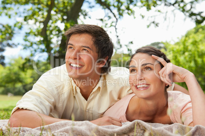Two friends looking upwards while lying on a blanket