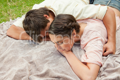 Man with his arm around his friend while lying on a blanket