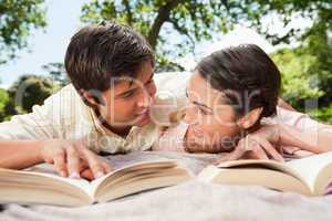 Two friends looking at each other while reading books on a blank