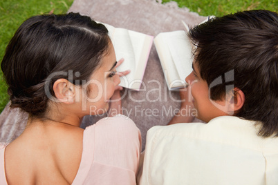 Rear view of two friends looking at each other while reading on