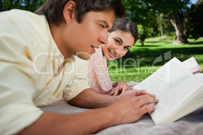Woman looks to the side while reading with her friend in a park