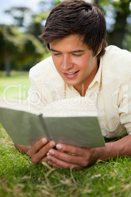 Man smiling while reading a book as he lies down