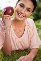 Woman holding an apple while lying in grass