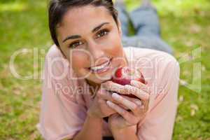 Woman looking ahead while holding an apple