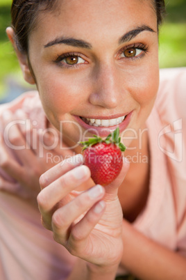 Woman offering a strawberry while lying in grass