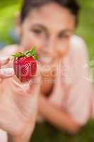Woman holding a strawberry at arms reach