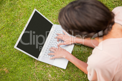Woman using a laptop while lying in grass
