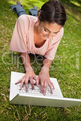 Woman smiling as she uses a laptop while lying down