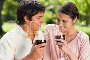 Two friends holding glasses of wine in a park