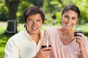 Two friends looking ahead while holding glasses of wine
