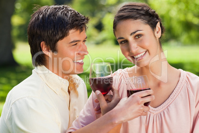 Two friends smiling while linking their arms and holding glasses