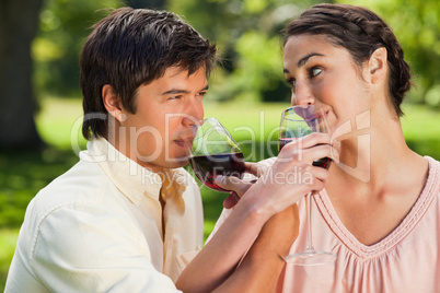 Two friends drinking wine while linking arms