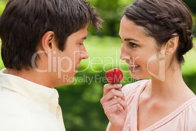 Woman looking at her friend while holding a strawberry