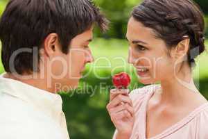 Woman looking at her friend while holding a strawberry