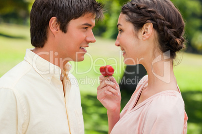 Man smiling while being offered a strawberry by his friend