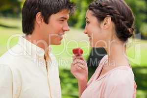 Man smiling while being offered a strawberry by his friend