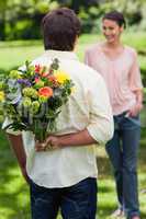 Man about to surprise his friend with a bouquet of flowers