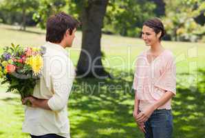Woman smiling as her friend approaches her with flowers