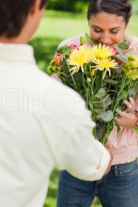 Woman smells flowers with are being given to her by a friend