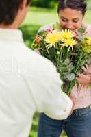 Woman smells flowers with are being given to her by a friend
