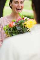 Woman laughing as she is being presented with flowers