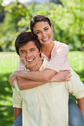 Woman looking ahead while her friend is carrying her on his back