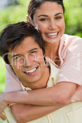 Close-up of a woman looking ahead while her friend is carrying h