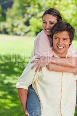 Woman holding her friend tight as he is carrying her on his back