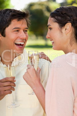 Two friends laughing while holding glasses of champagne