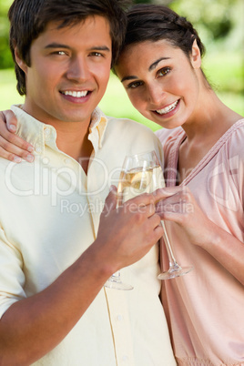 Woman leaning against her friend while they touch glasses of cha