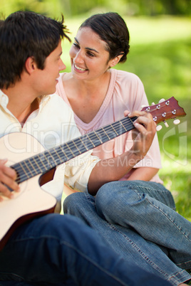 Man playing a guitar while looking at his friend