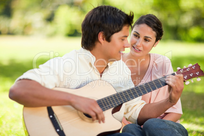 Man playing the guitar while his friend watches him