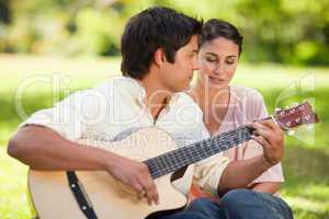 Woman closes her eyes while listening to her friend play the gui