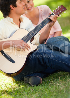 Man playing the guitar while his friend is listening to him