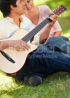 Man playing the guitar while his friend is listening to him