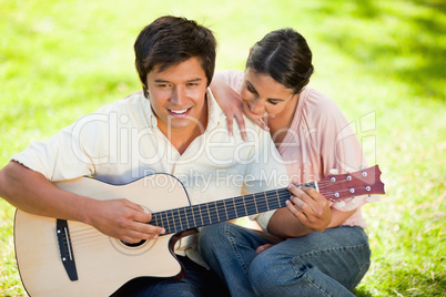 Woman leaning while leaning on her friends shoulder as he plays