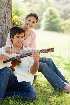 Woman holding her friend as her plays the guitar