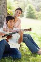 Woman holding her friend as her plays the guitar