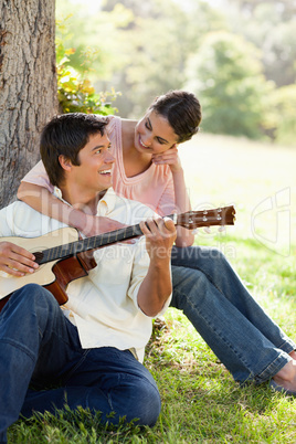 Woman looking at her friend while holding him as her plays the g