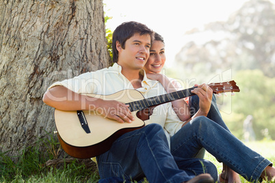 Man playing the guitar while looking into the distance with his