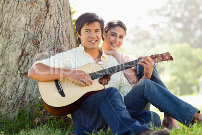 Man playing the guitar while ahead with his friend