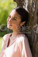 Woman looking into the distance while sitting against a tree