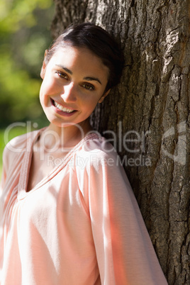 Woman looking to her side while sitting against a tree